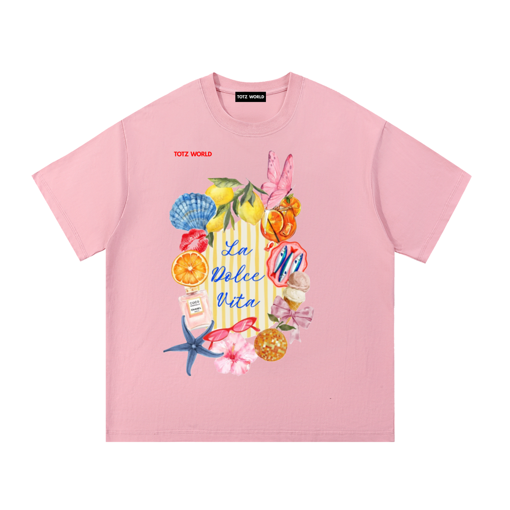 A  TOTZ WORLD light pink short-sleeve T-shirt with a colorful beach-themed graphic print on the front featuring seashells, starfish, and the text 'La Dolce Vita' 