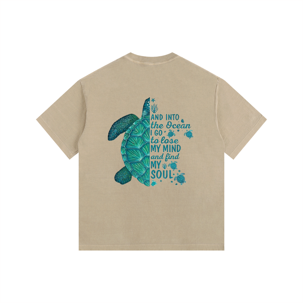 A khaki short-sleeve t-shirt with a graphic on the back featuring a teal sea turtle and the text 'AND INTO THE OCEAN I GO TO LOVE MY MIND and find MY SOUL' in teal, shown against a plain white background.