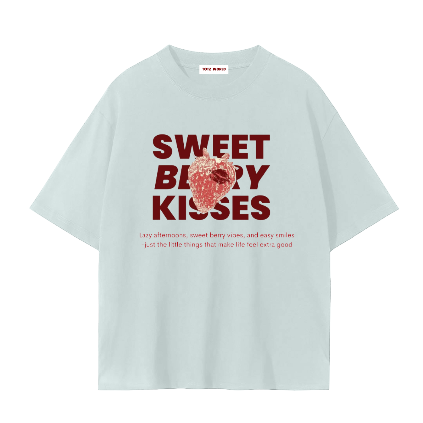 A light blue premium TOTZ WORLD cotton short-sleeve t-shirt with a graphic print on the front. The print features the words 'SWEET BERRY KISSES' in dark red, overlaid with a red and white strawberry illustration, and a small tagline underneath in pink.