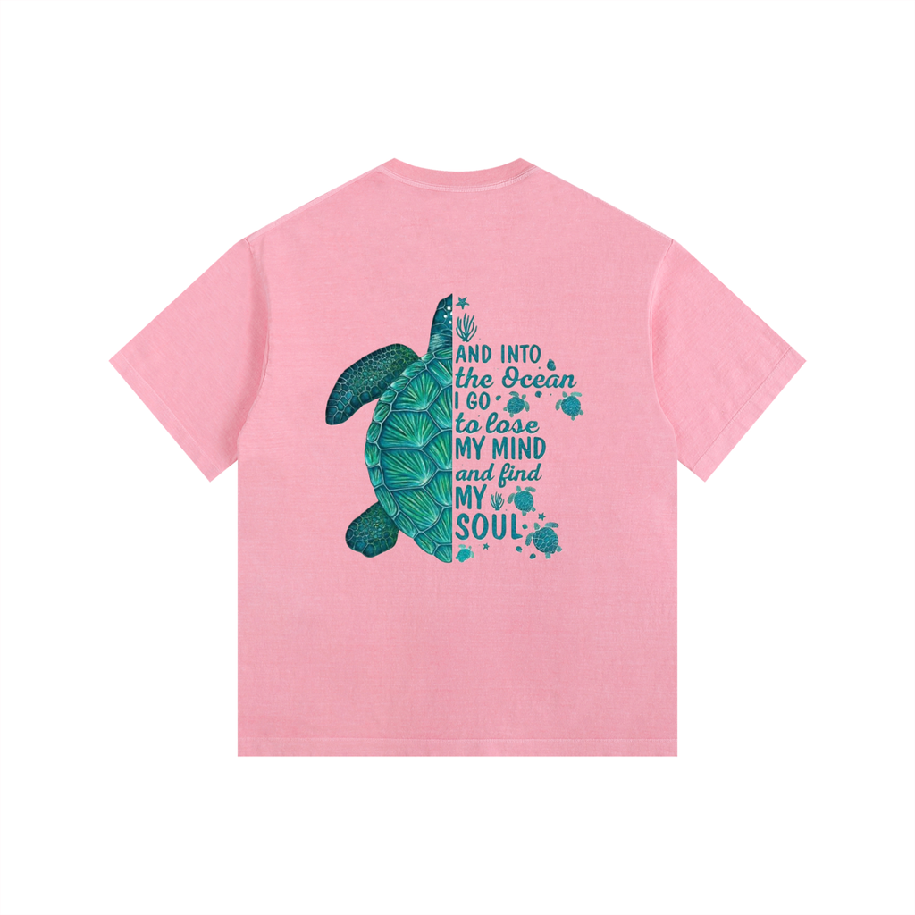 A pink short-sleeve t-shirt with a graphic on the back featuring a teal sea turtle and the text 'AND INTO the Ocean I go to lose MY MIND and find MY SOUL' in teal lettering, shown on a plain white background.