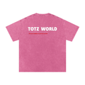 A pink short-sleeve t-shirt with a Snow-wash texture, featuring the words 'TOTZ WORLD' in bold white letters and a smaller red slogan underneath, displayed on a clean white background.