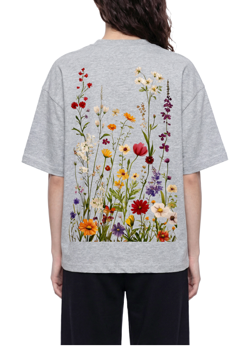 A person shown from the back wearing a light gray oversized T-shirt with a large multicolor wildflower print across the back, paired with black pants, against a plain white background.