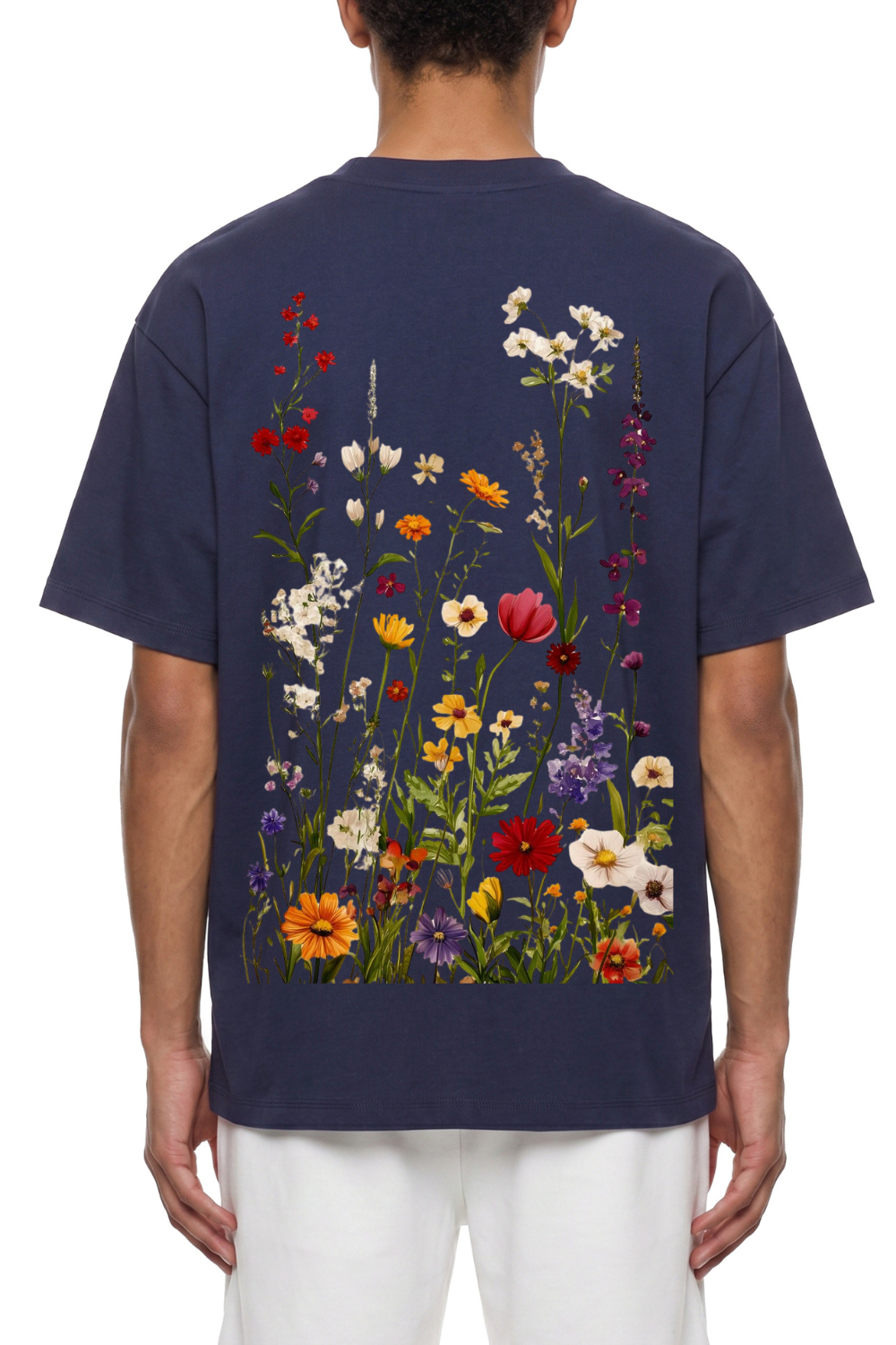 A man viewed from the back wearing a navy blue t-shirt with a large, colorful wildflower print across the back, paired with white pants.